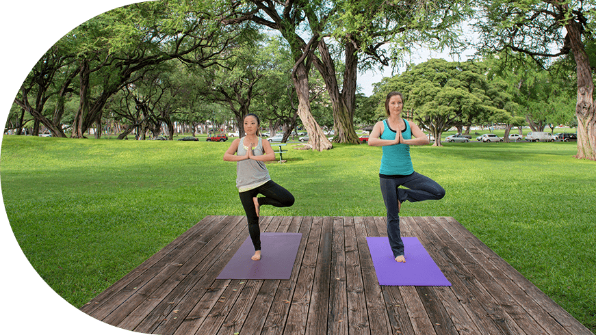 Two women doing yoga in a park