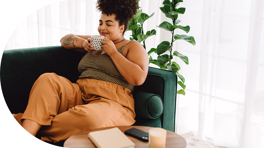 Woman sitting on the couch sipping from a mug.